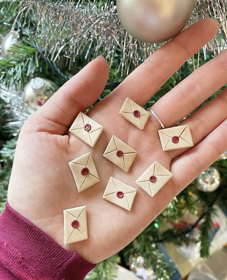 a person's hand holding several small origami pieces in front of a christmas tree