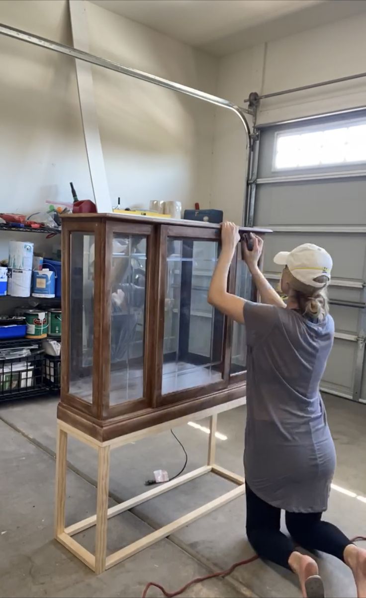 a woman working on a display case in a garage