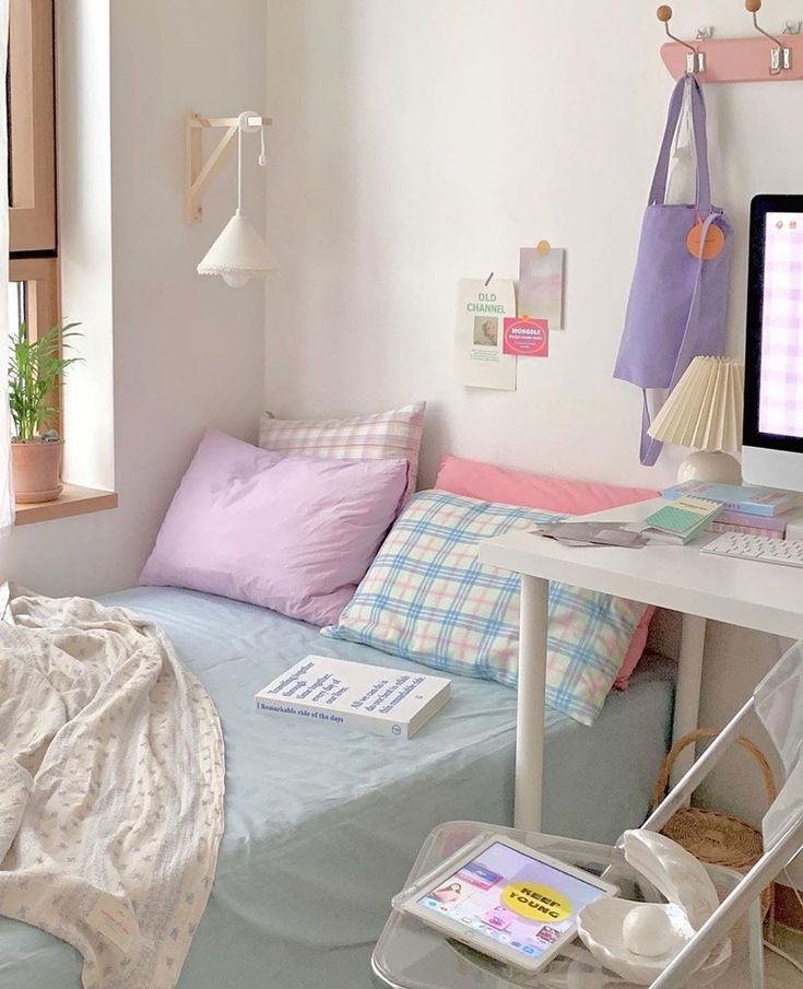 a small bedroom with a bed, desk and computer monitor on top of the table