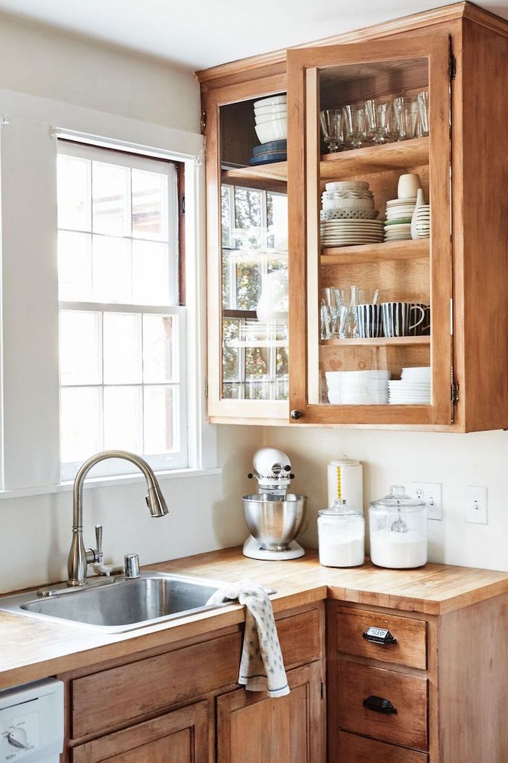 a kitchen with wooden cabinets and white dishes