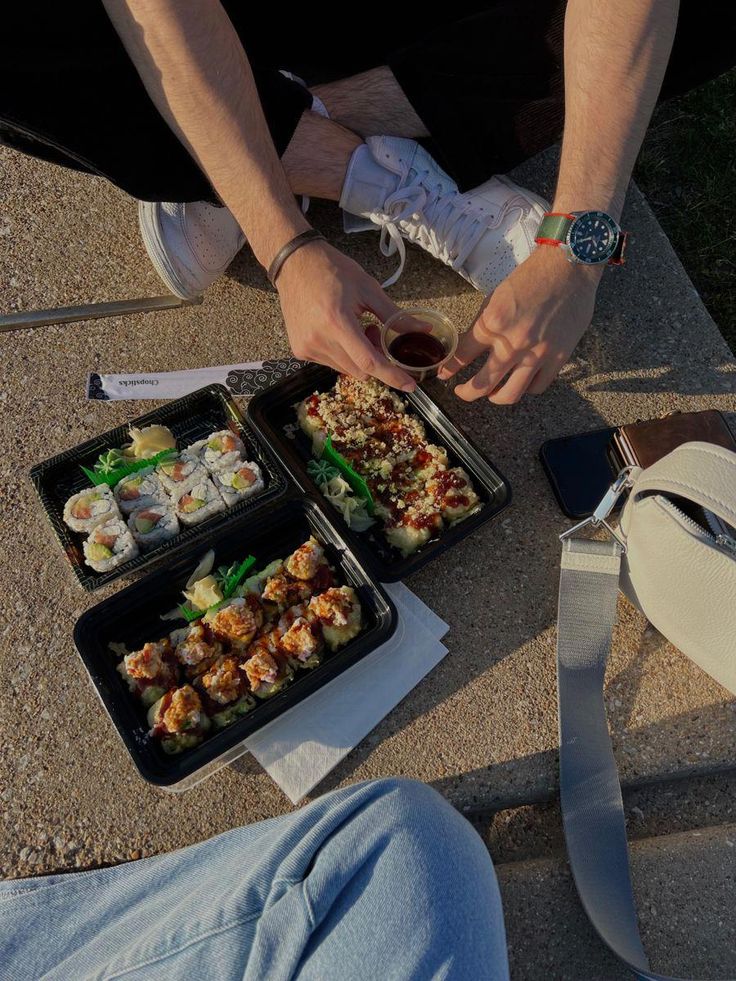 two people sitting on the ground eating sushi