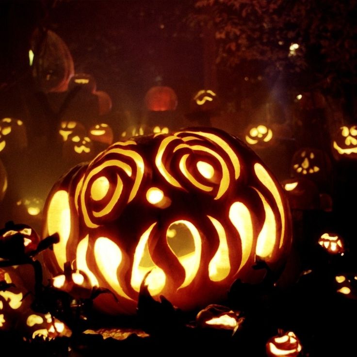 a pumpkin carved into the shape of a face surrounded by jack - o - lanterns