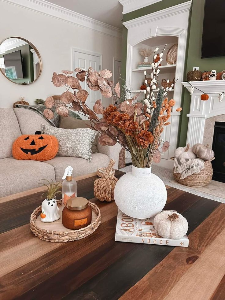 a living room decorated for halloween with pumpkins, candles and other decorations on the coffee table