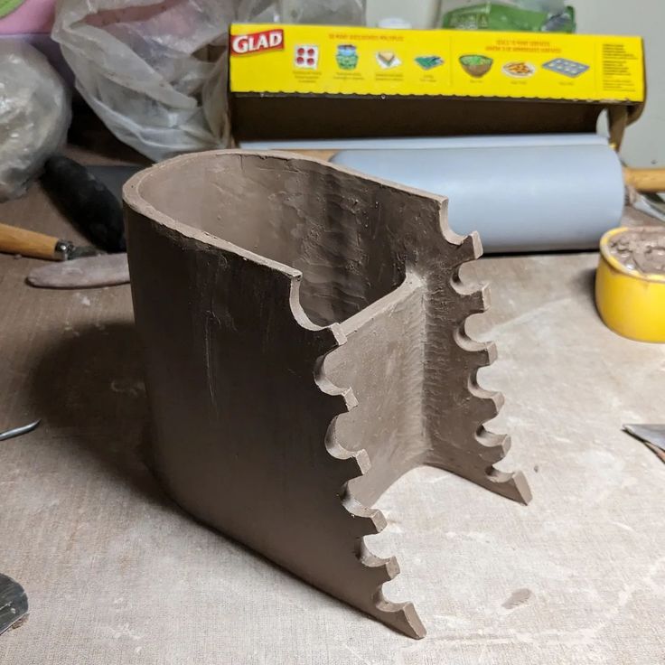 a close up of a metal object on a table with tools and other items in the background