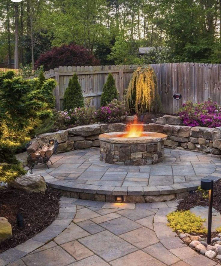 an outdoor fire pit surrounded by landscaping