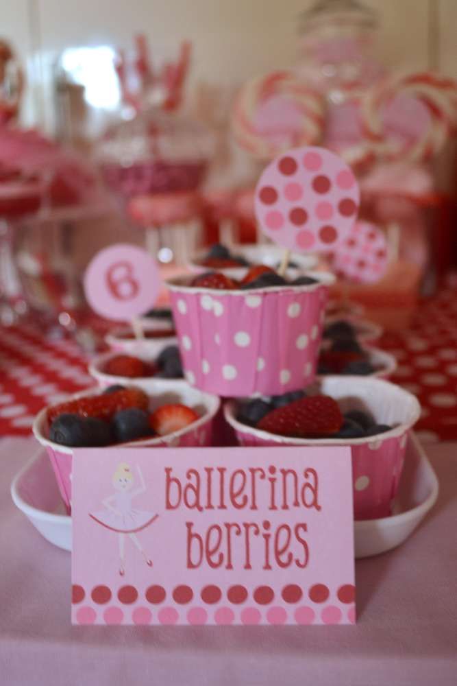 a table topped with cups filled with strawberries and cupcakes on top of plates