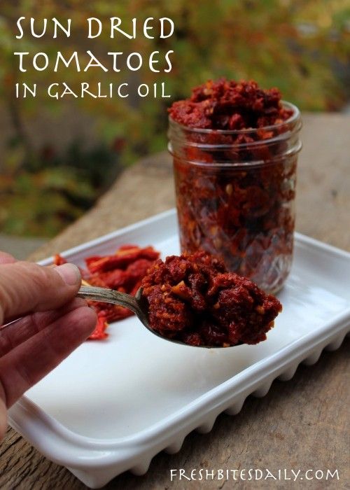 sun dried tomatoes in garlic oil being spooned into a small container with the lid open