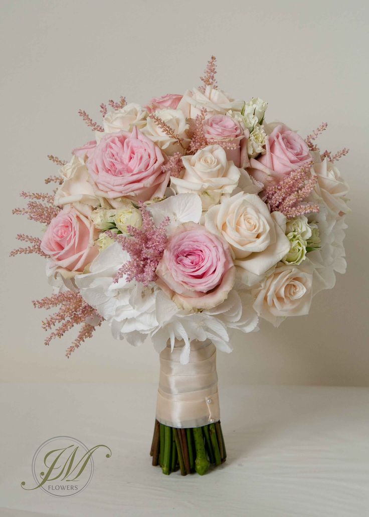 a bridal bouquet with pink and white flowers in a vase on a table top