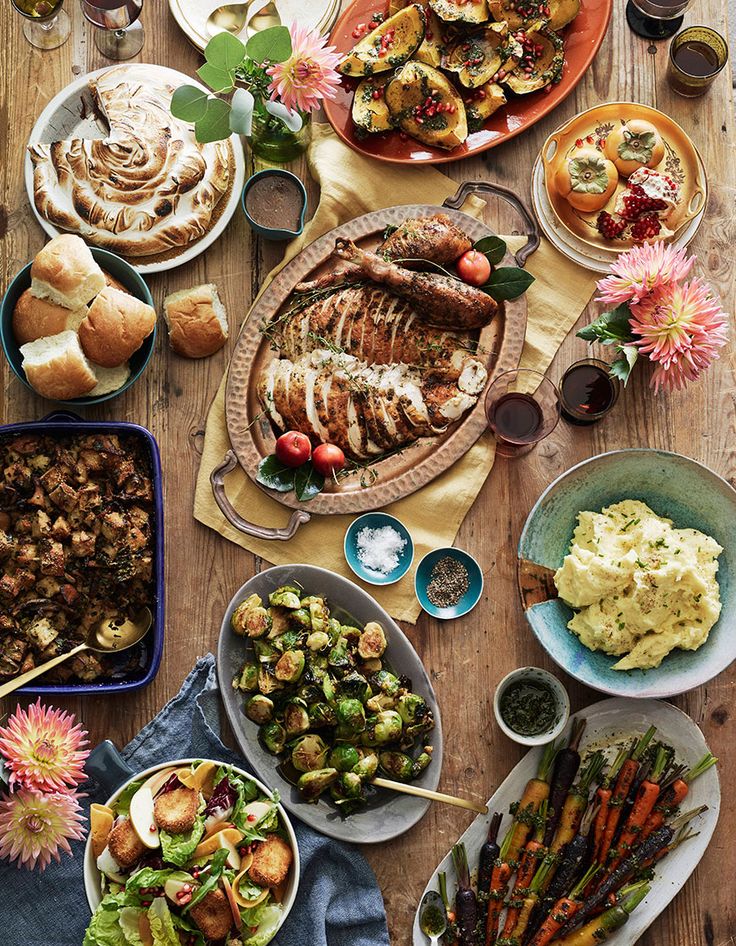 a wooden table topped with lots of plates and bowls filled with different types of food