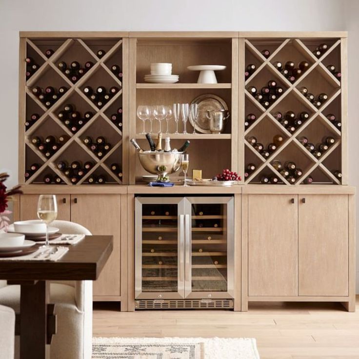 a dining room with wine bottles and glasses on the shelves in front of the table