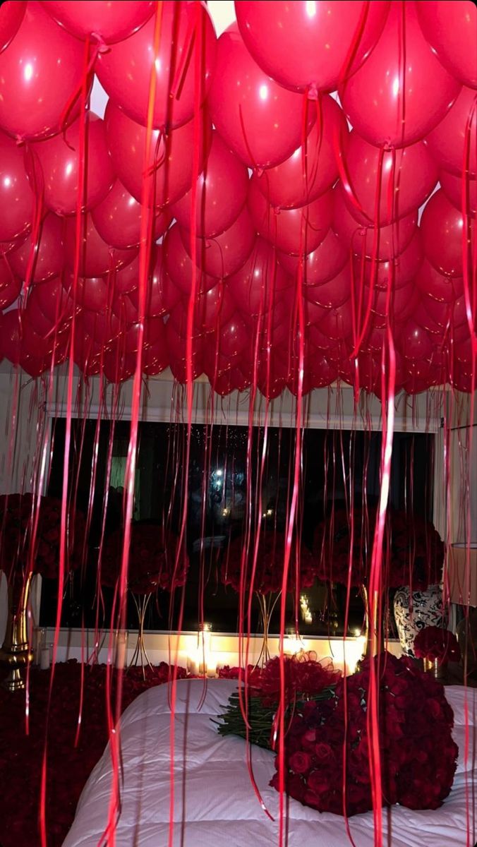 red balloons are hanging from the ceiling above a bed