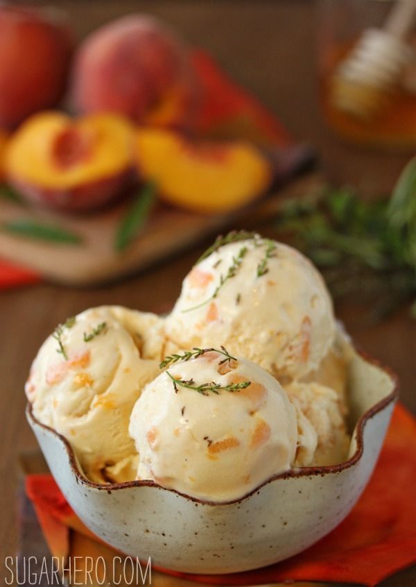 a bowl filled with ice cream sitting on top of a table next to sliced peaches