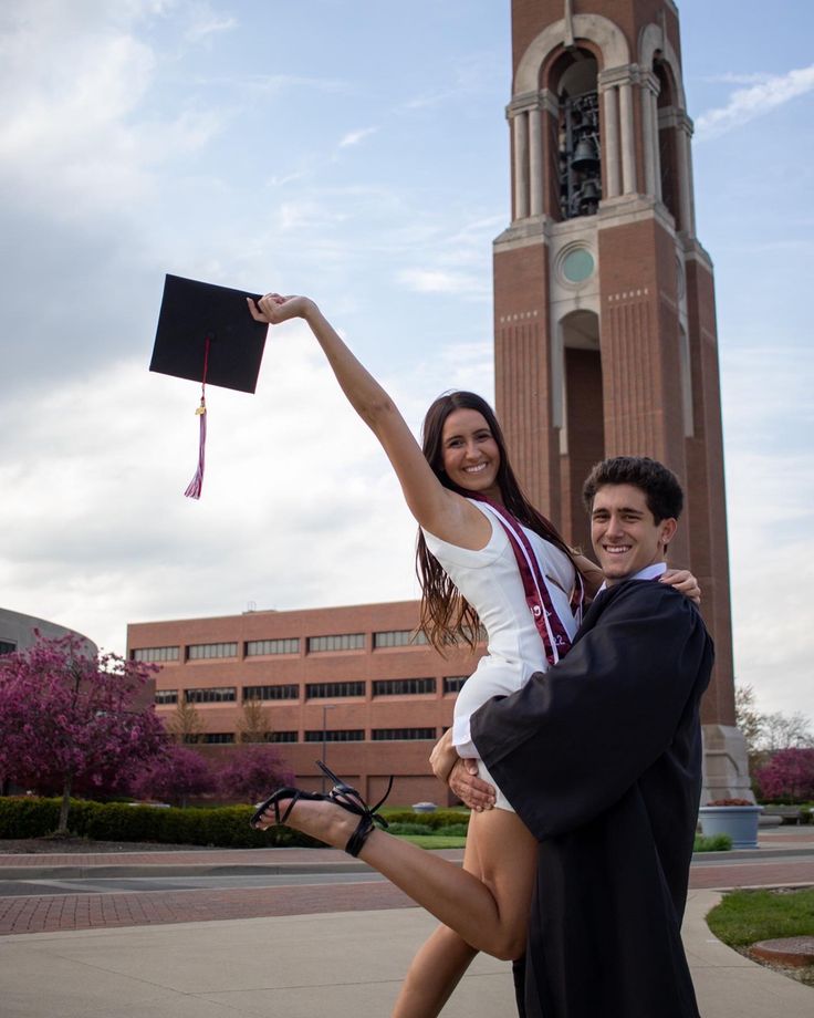 a man and woman posing for a picture in front of a building with a clock tower