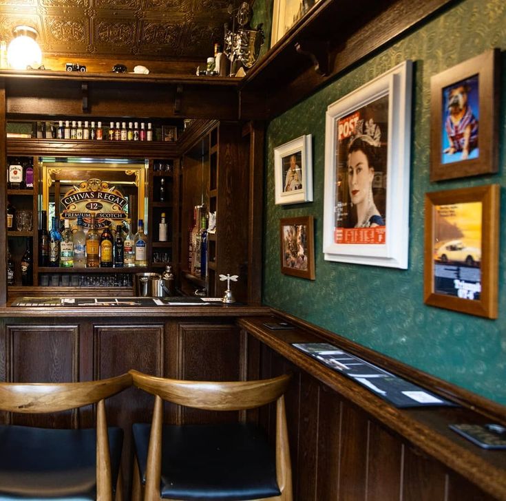 two wooden chairs sitting in front of a bar with pictures on the wall behind it