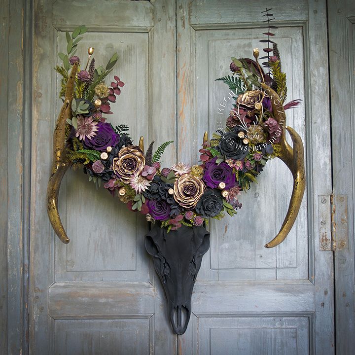 an antelope with flowers on it's head is displayed in front of a door