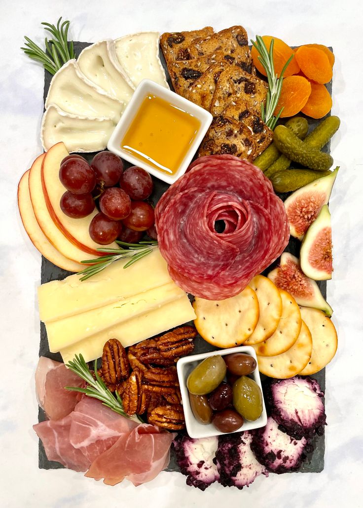 an assortment of cheeses, meats, and other foods are arranged on a platter