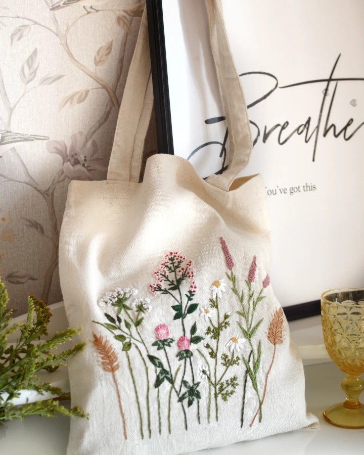 a white bag sitting on top of a table next to a vase and framed photograph