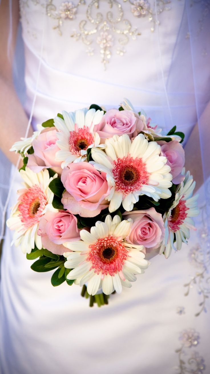 a bride holding a bouquet of pink and white flowers