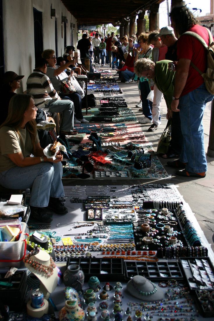 a group of people standing next to each other in front of a table full of jewelry