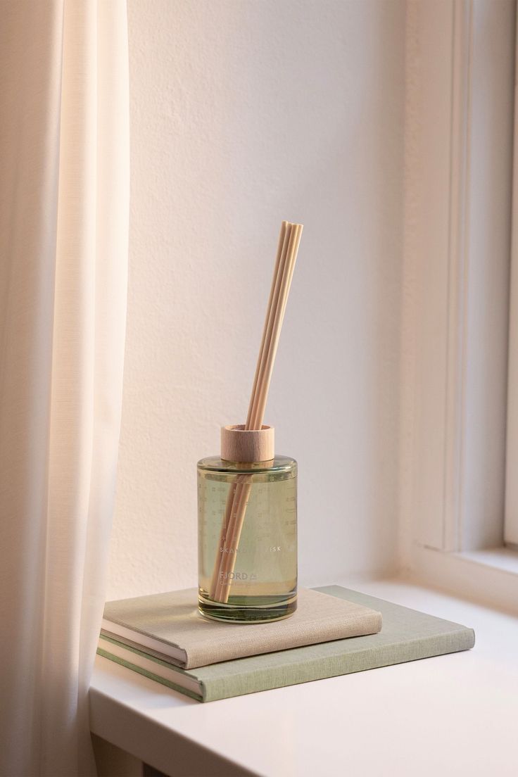 a glass jar with two straws sitting on top of a book next to a window