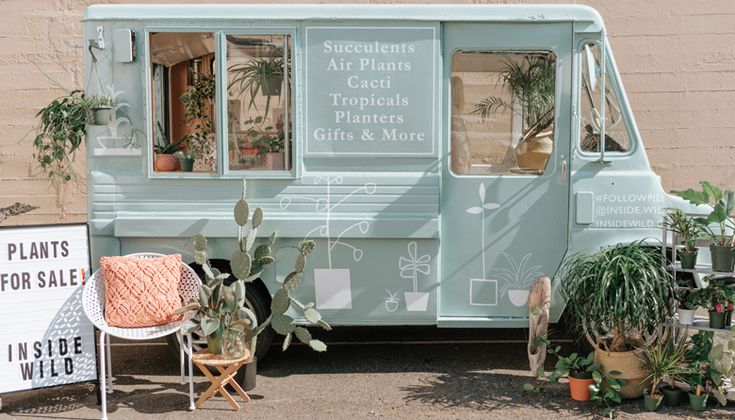 an ice cream truck parked in front of a building with potted plants on the side