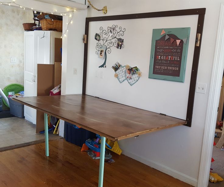 a wooden table sitting in the middle of a room next to a wall with pictures on it