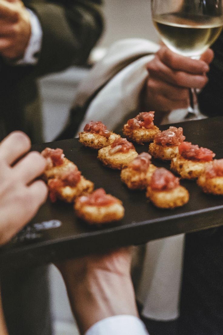 several people are holding trays with food and wine