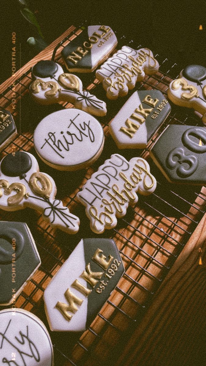 decorated cookies are on a cooling rack in the dark, with gold and black decorations