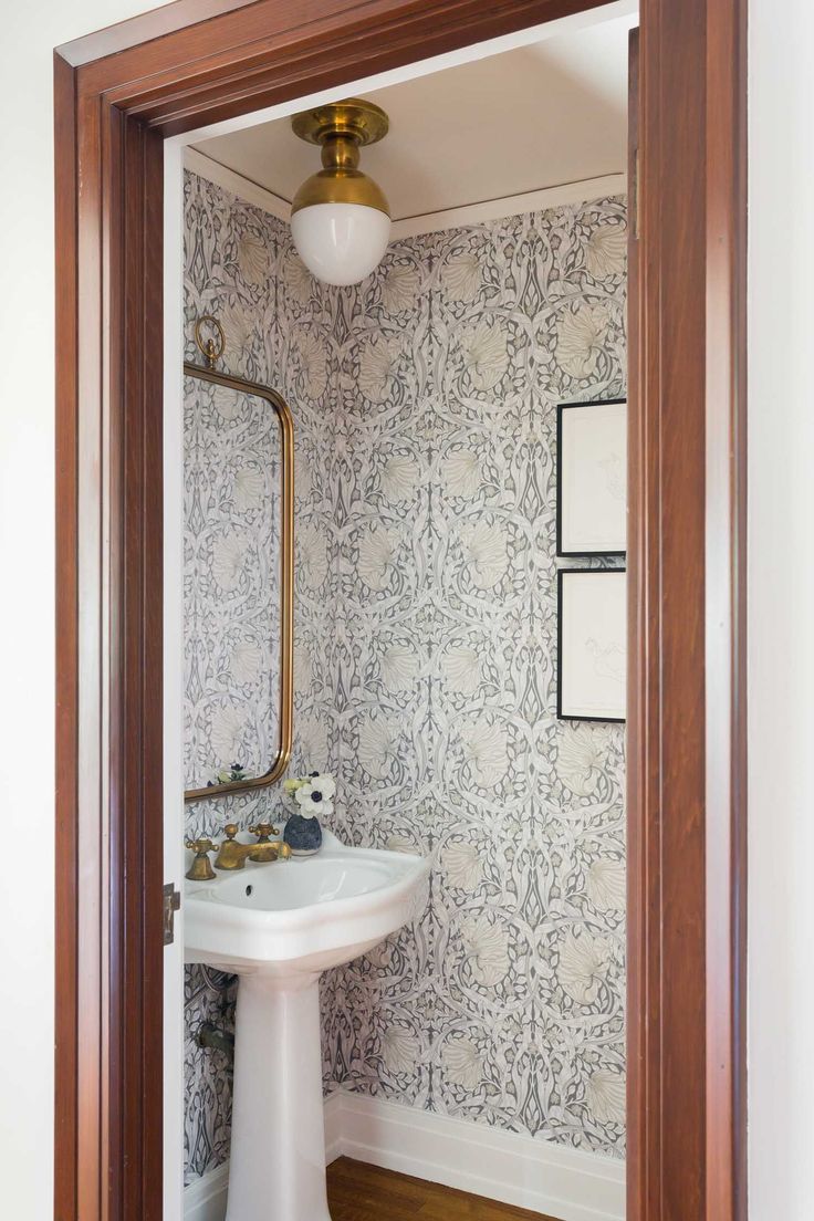 the bathroom is decorated with wallpaper and wood trimmings, along with a pedestal sink