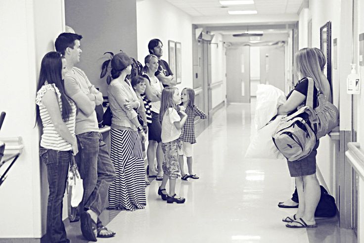 a group of people waiting in line at the end of a long hallway with doors