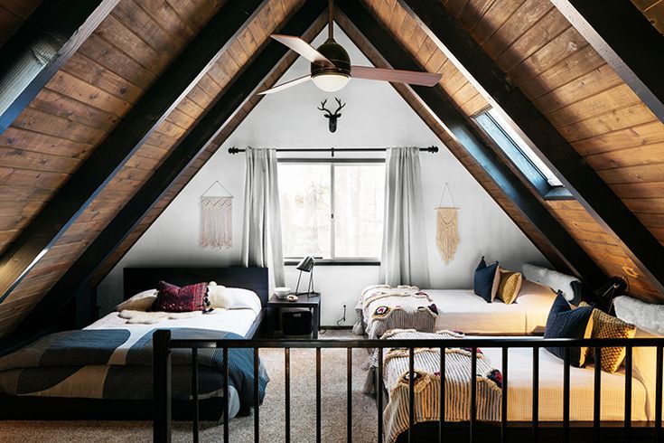 an attic bedroom with two beds and a ceiling fan in the middle of the room