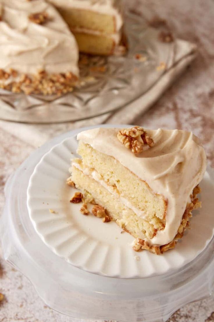 a piece of cake with white frosting and walnuts on top sitting on a plate