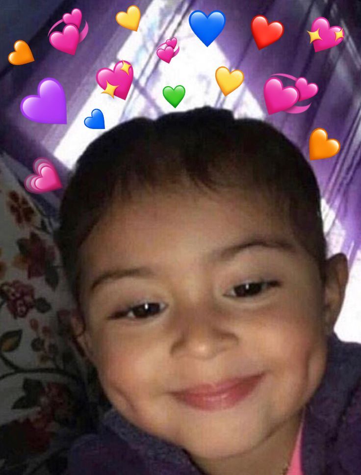 a little boy that is sitting down with hearts in the air above him and smiling