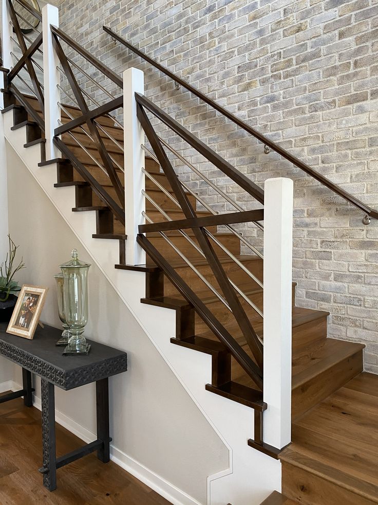 there is a vase on the table next to the stair case in this room with brick wall and wood flooring