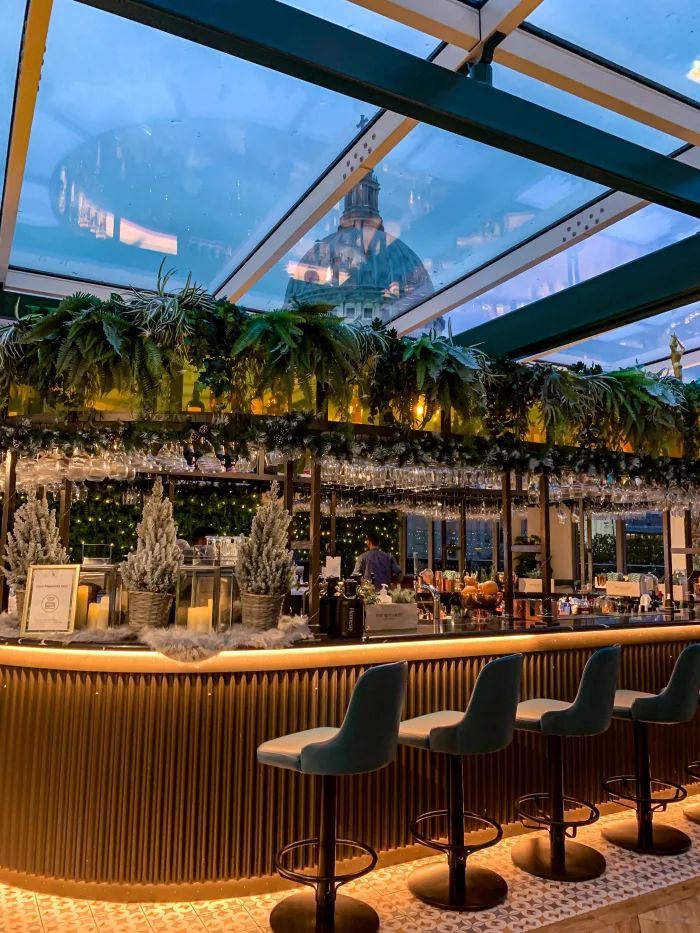 an indoor bar with several chairs and plants on the wall, along with palm trees