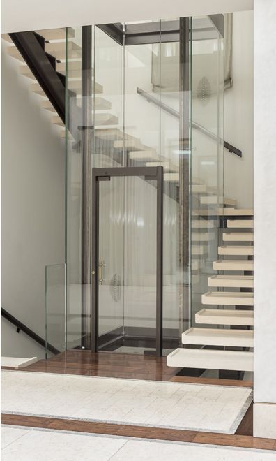 an open glass door leading up to a stair case in a building with marble steps