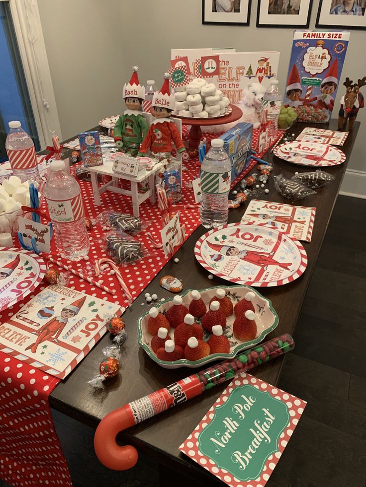 a long table covered with red and white christmas desserts, plates and napkins