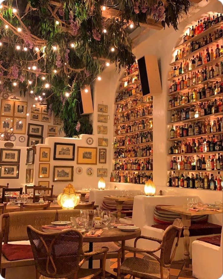 the interior of a restaurant with lots of bottles on the wall and lights hanging from the ceiling