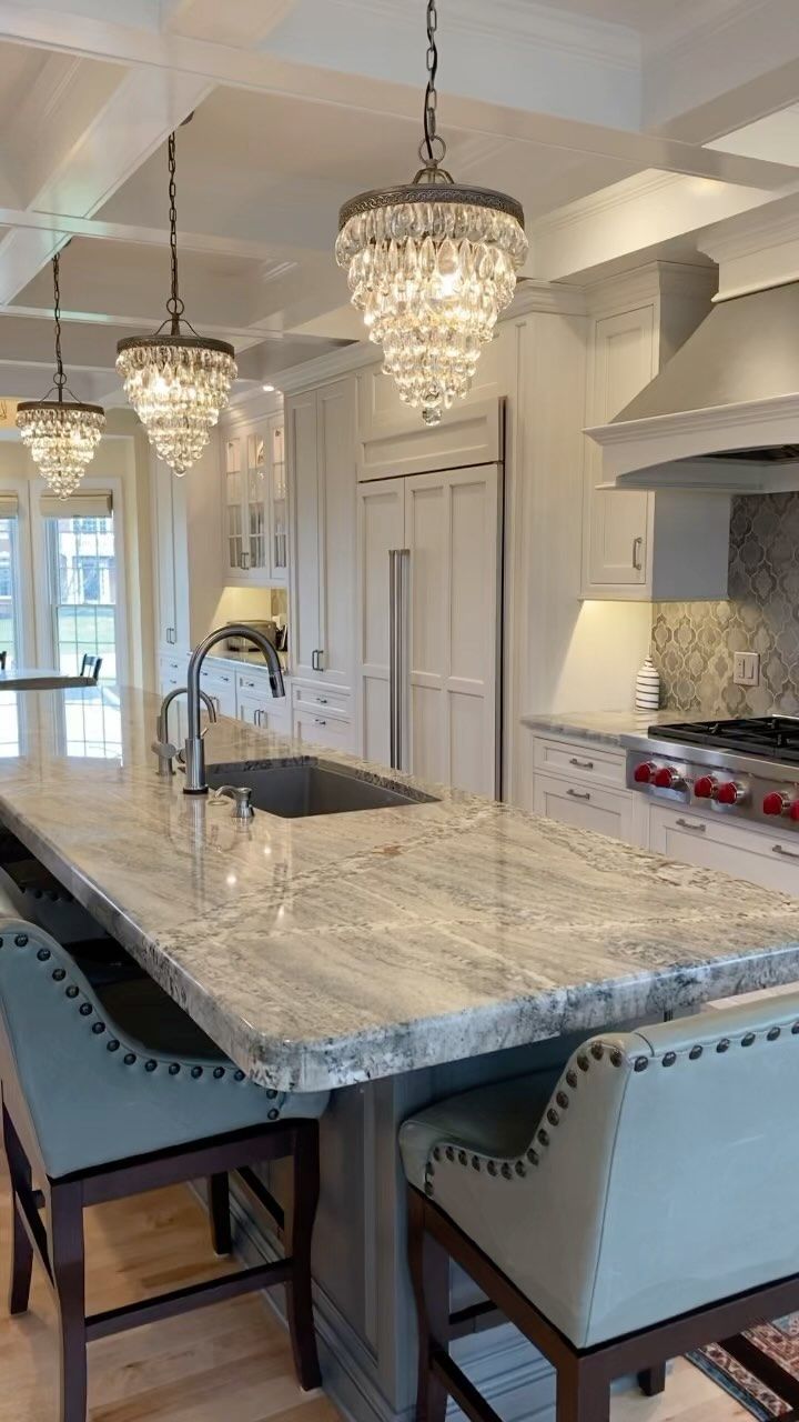 a large kitchen with an island and chandelier hanging from it's ceiling