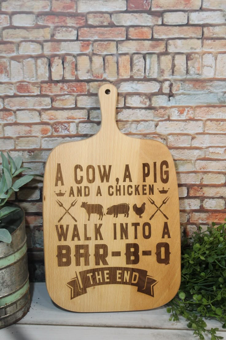 a wooden cutting board sitting on top of a shelf next to a plant and brick wall