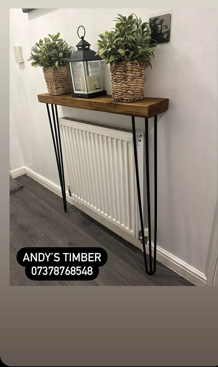 two plants are sitting on top of a wooden shelf next to a radiator