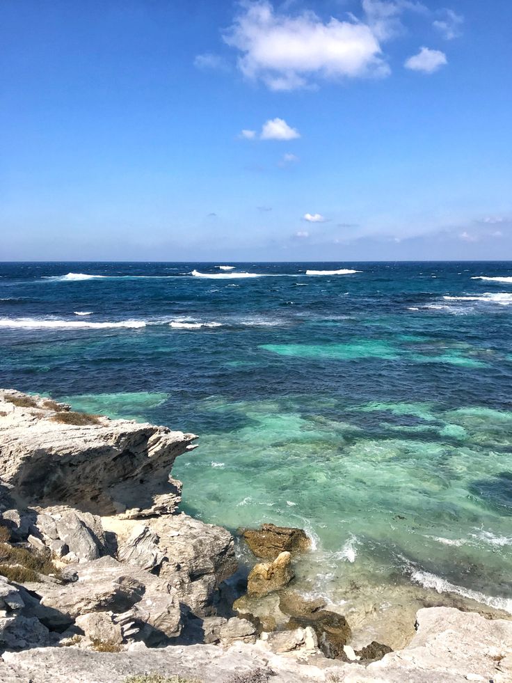 the ocean is clear and blue with waves coming in from the rocks on the shore