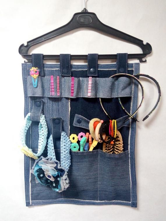 a denim bag with various items in it hanging on a wall