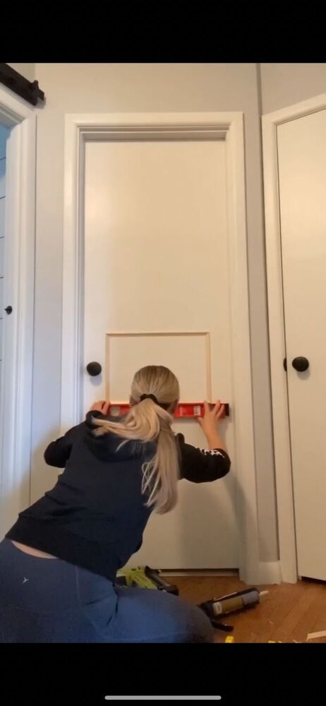 a woman kneeling down on the floor in front of a door with a red handle