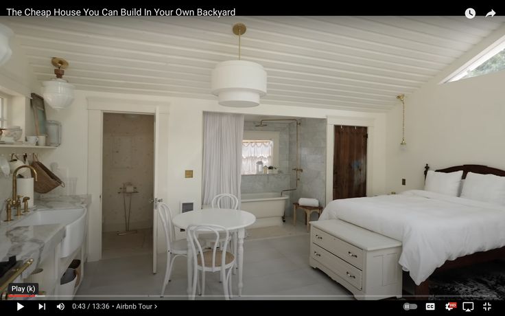 a bedroom with a bed, table and chairs next to a bathtub in the corner