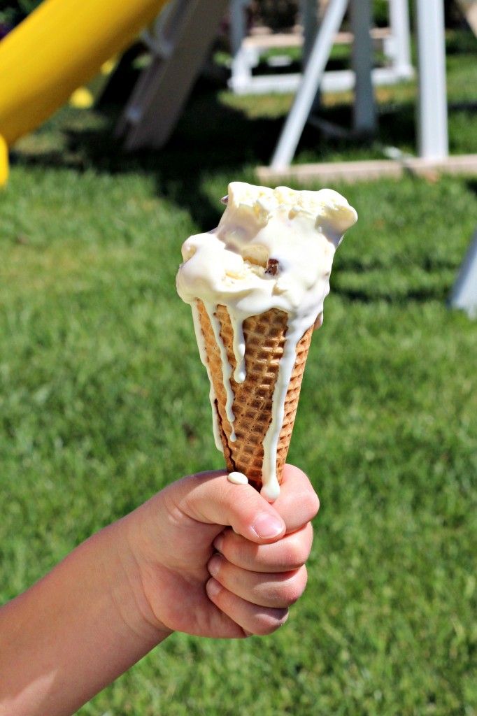 someone holding up an ice cream cone with white icing on it in their hand