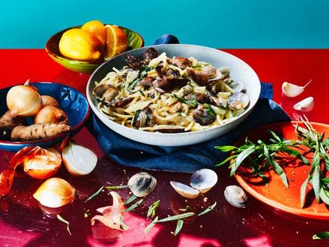 bowls of food are sitting on a red and blue tablecloth next to oranges