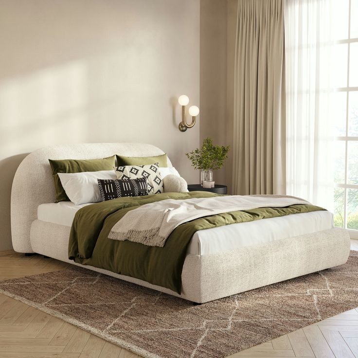 a large bed sitting on top of a wooden floor next to a window with curtains