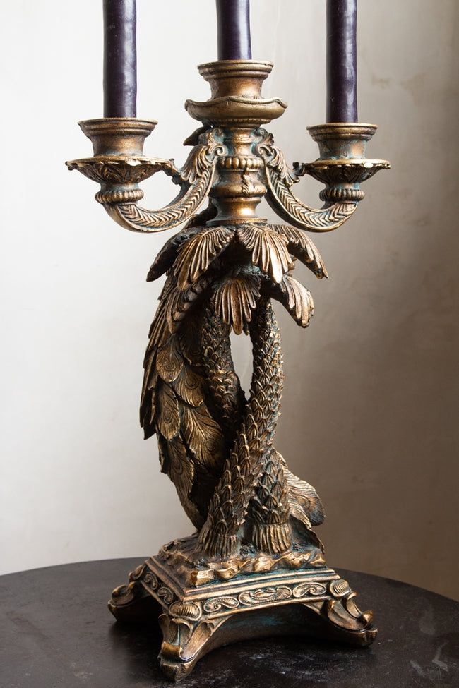 an ornately decorated candelabra with three lit candles on the top and bottom