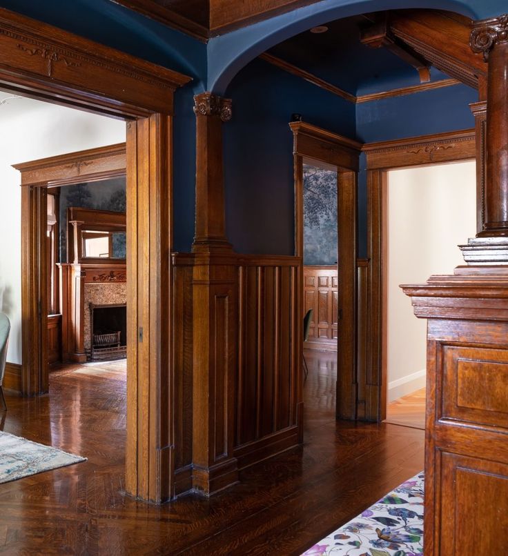 an empty room with blue walls and wood trimming on the ceiling, along with a fireplace